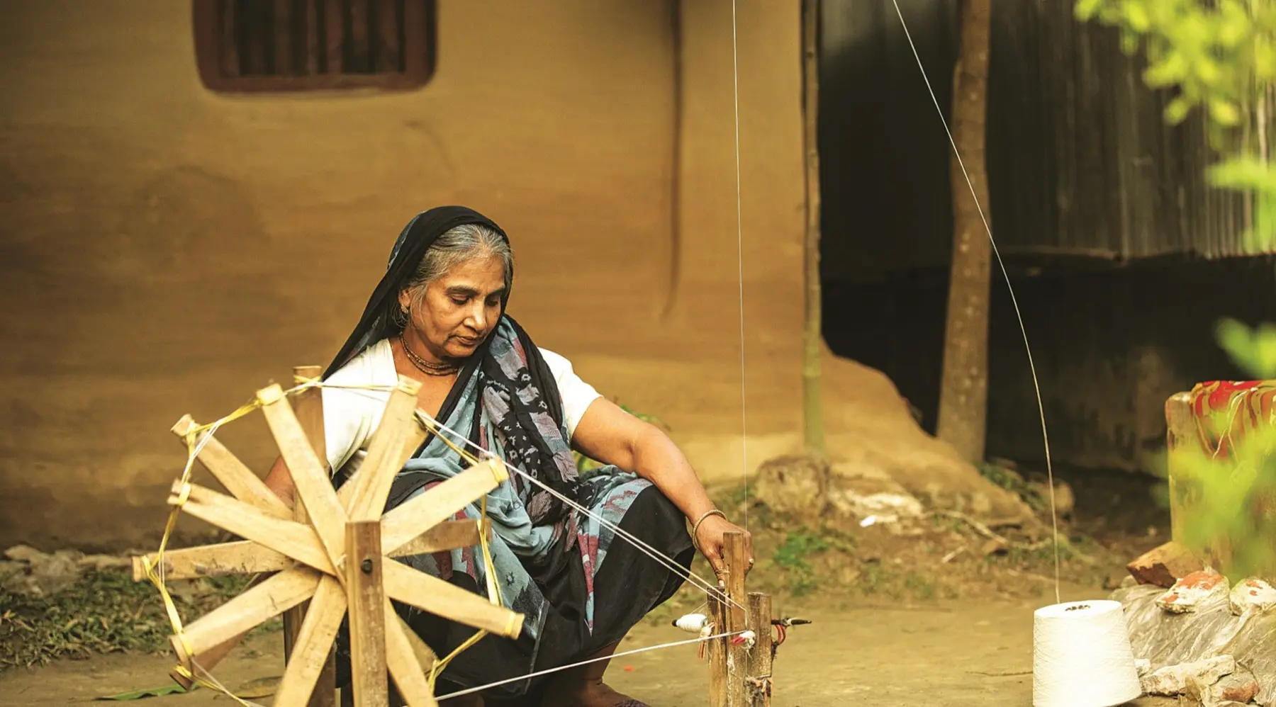 Hands spinning thread on a traditional wooden charkha in Bangladesh